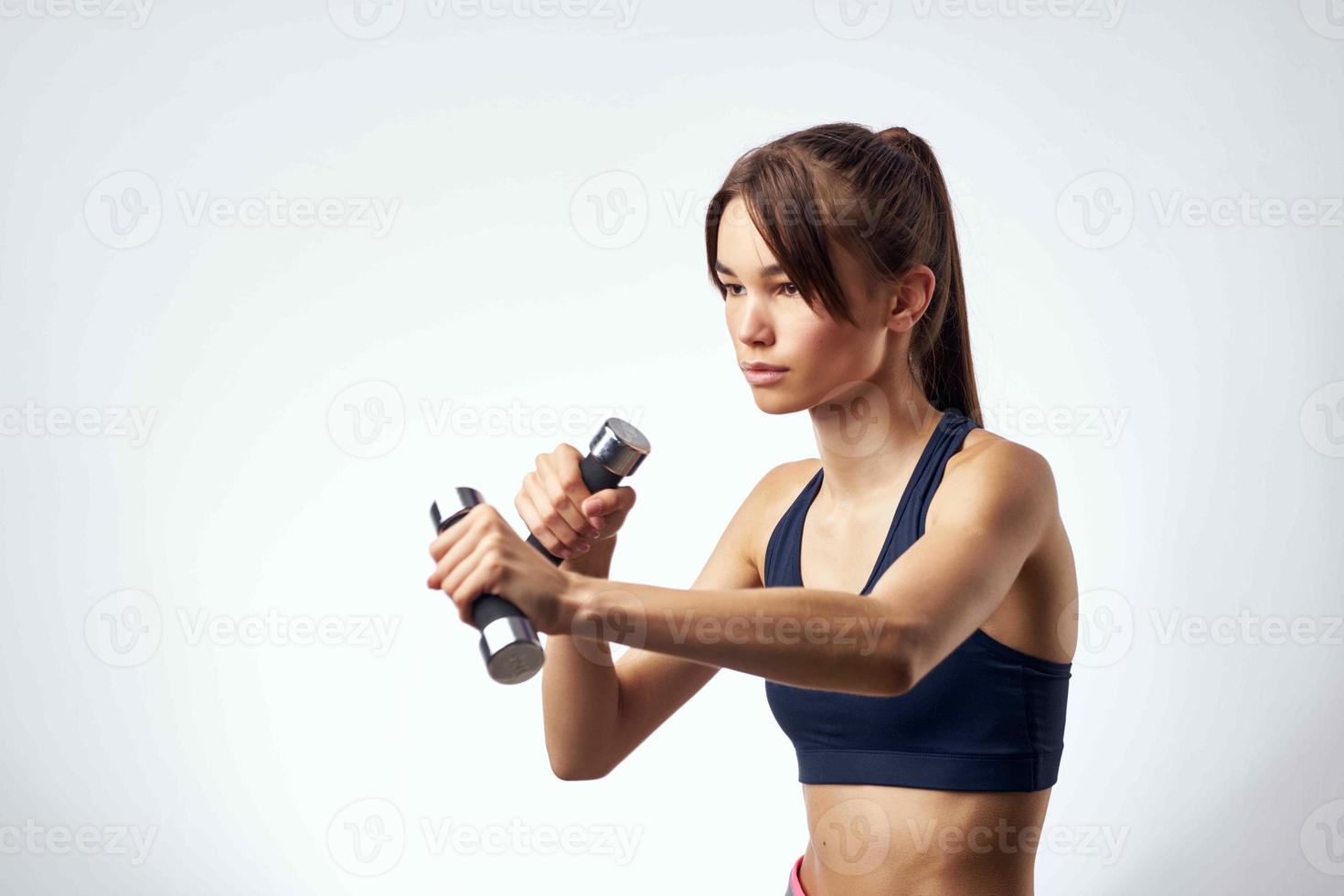 athletic slim woman workout with dumbbells fitness light background photo