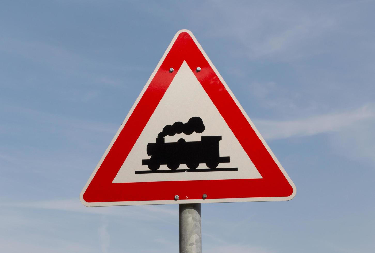 road sign railway crossing ahead against blue sky photo