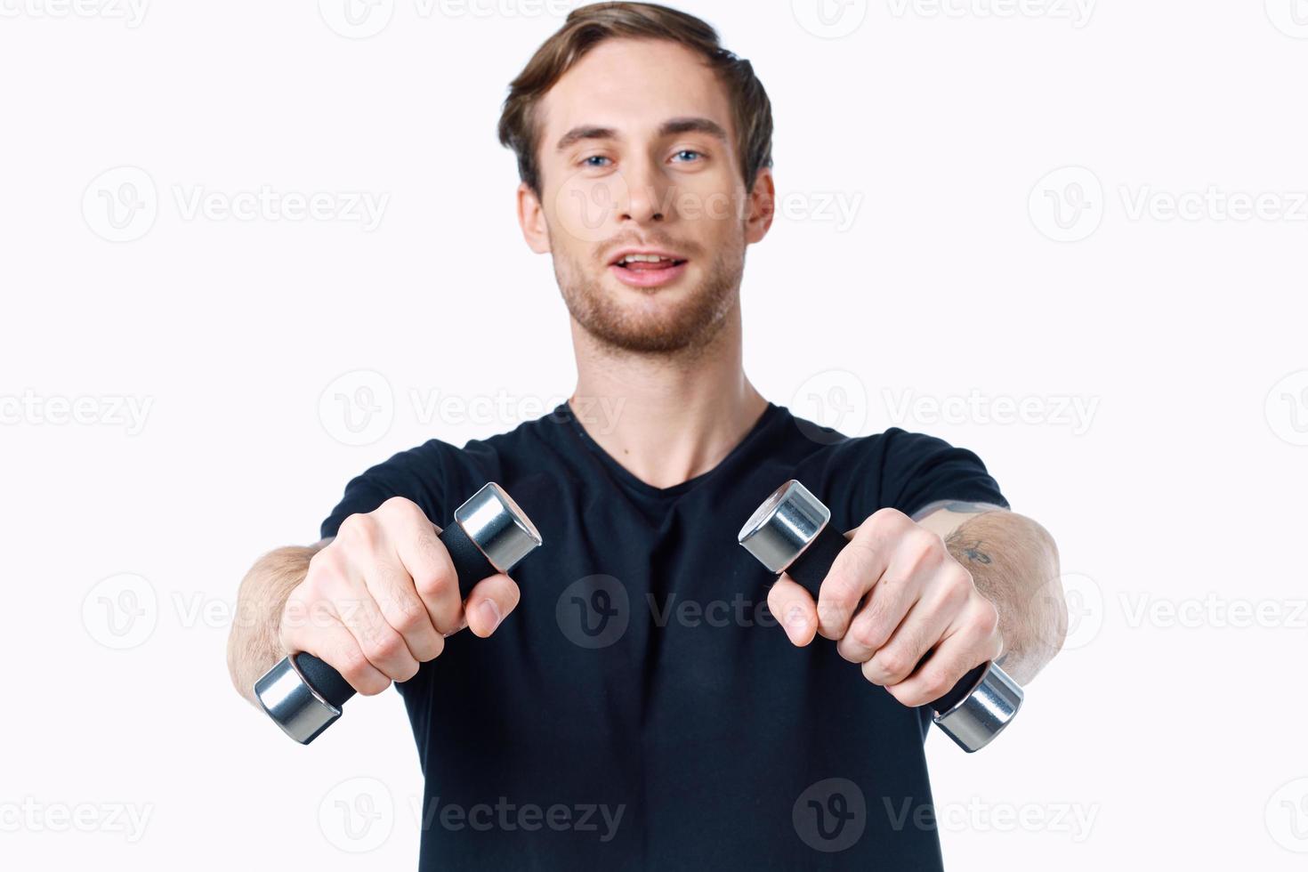 cute young man with dumbbells in hands goes in for sports on white background cropped view photo