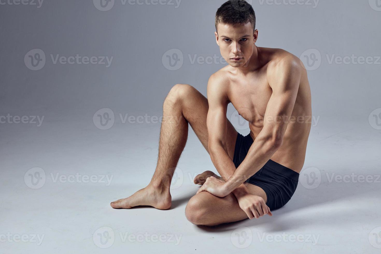 male athlete sitting on floor with pumped up body posing photo