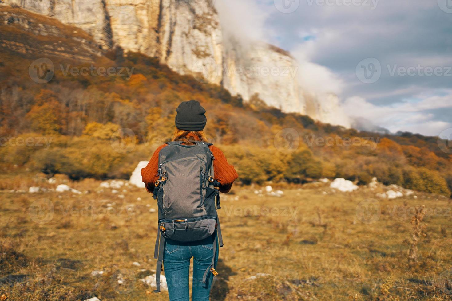 a traveler with a backpack in a denim hat are walking on the nature mountains photo