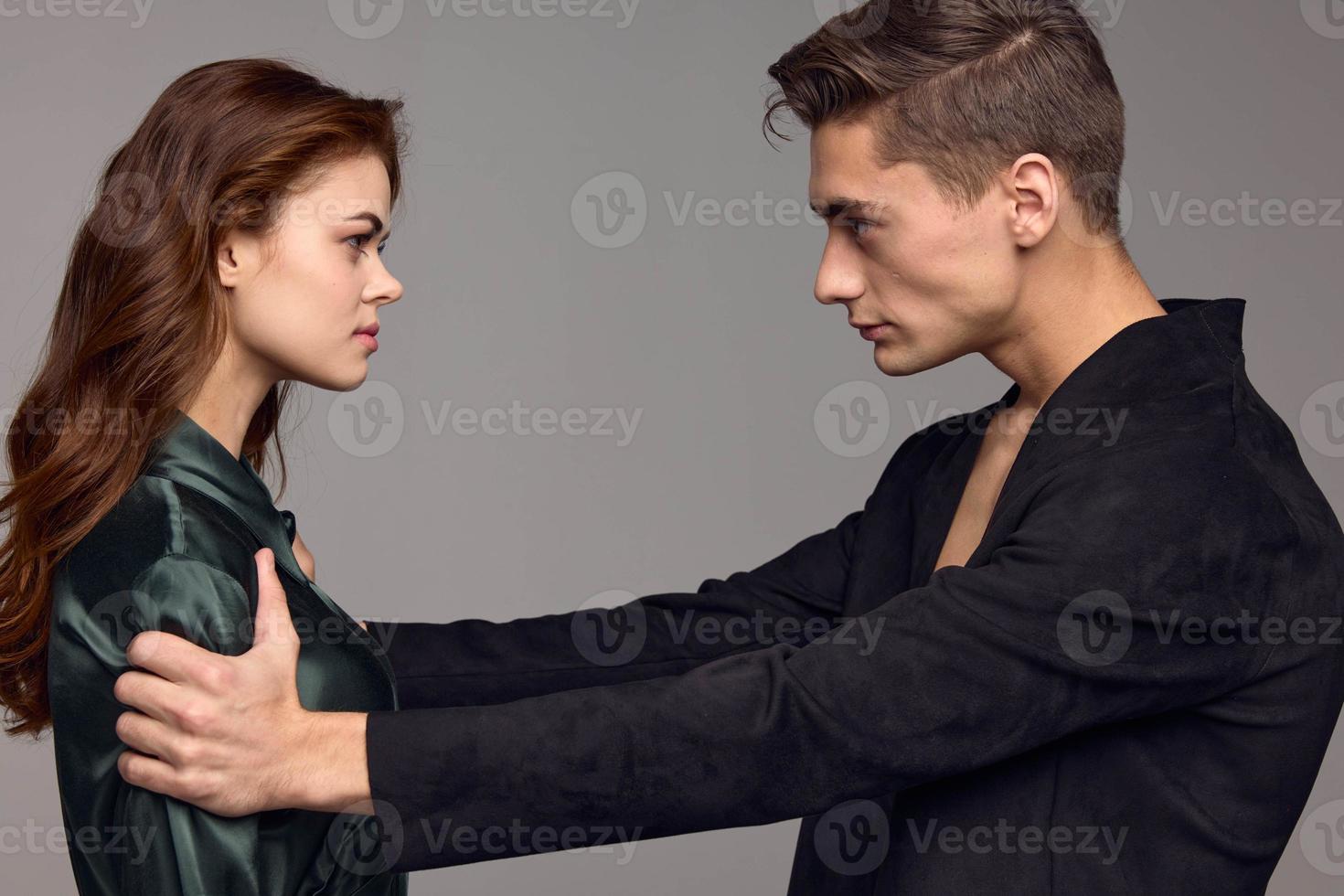 sexy hombre en un chaqueta y un mujer en un gris antecedentes opuesto cada otro foto