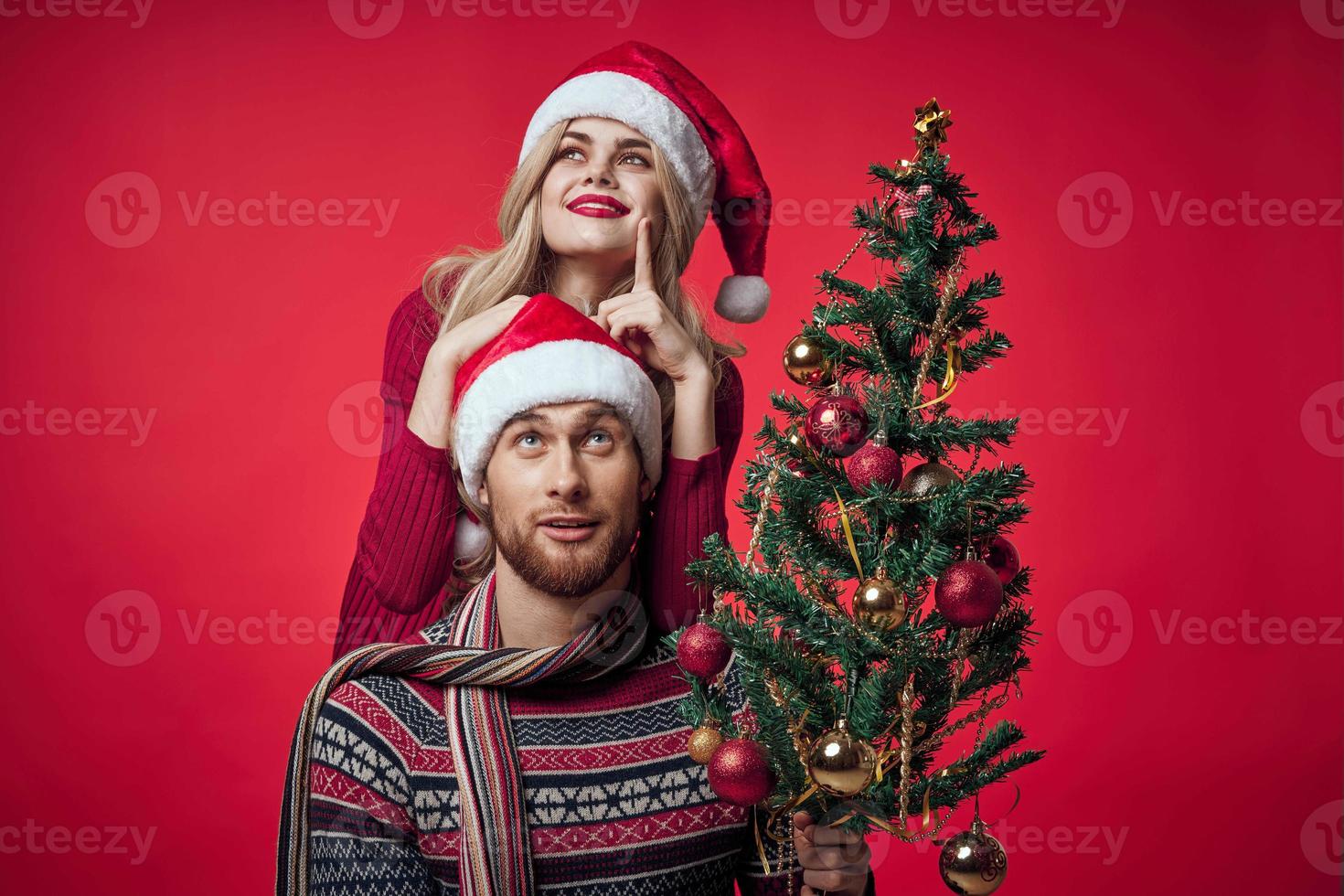 young married couple Christmas tree toys holiday joy red background photo