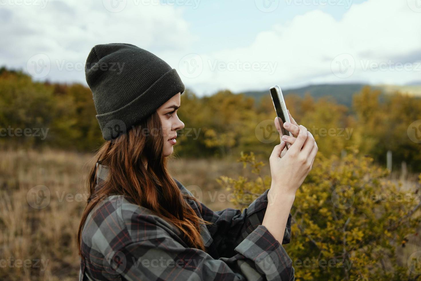 portrait of a woman in a medical mask with a phone on the background of an autumn forest in nature photo