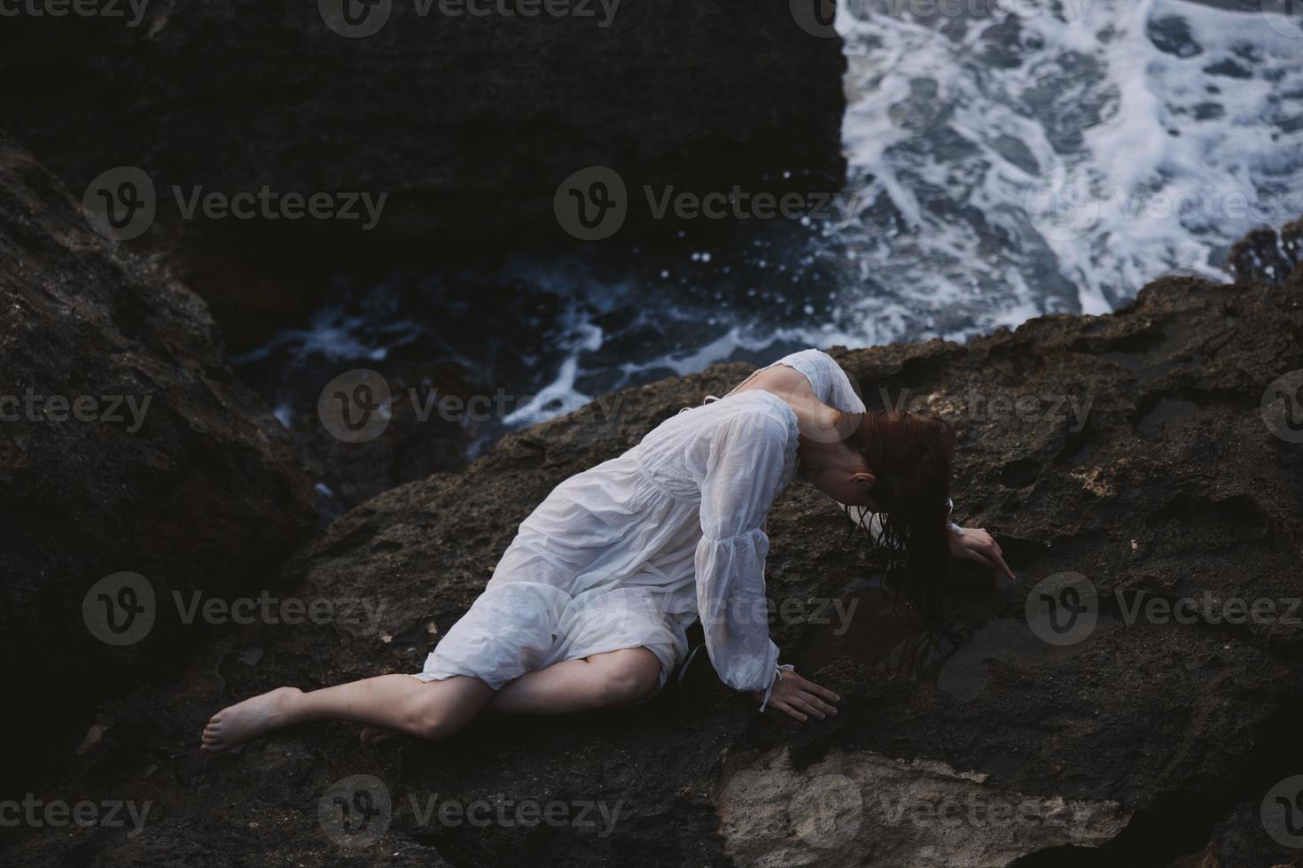 beautiful young woman in a white dress lying on a stone in a white dress Summer vacation concept photo