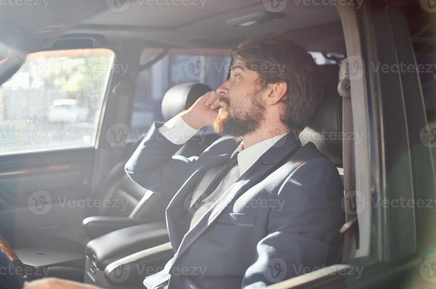 a man in a suit is sitting in the car and talking on the phone photo