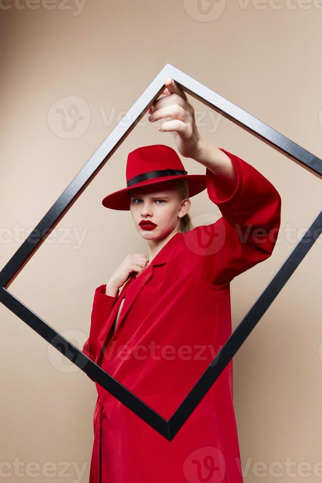 portrait of a woman frame in hand in red hat and jacket beige background photo