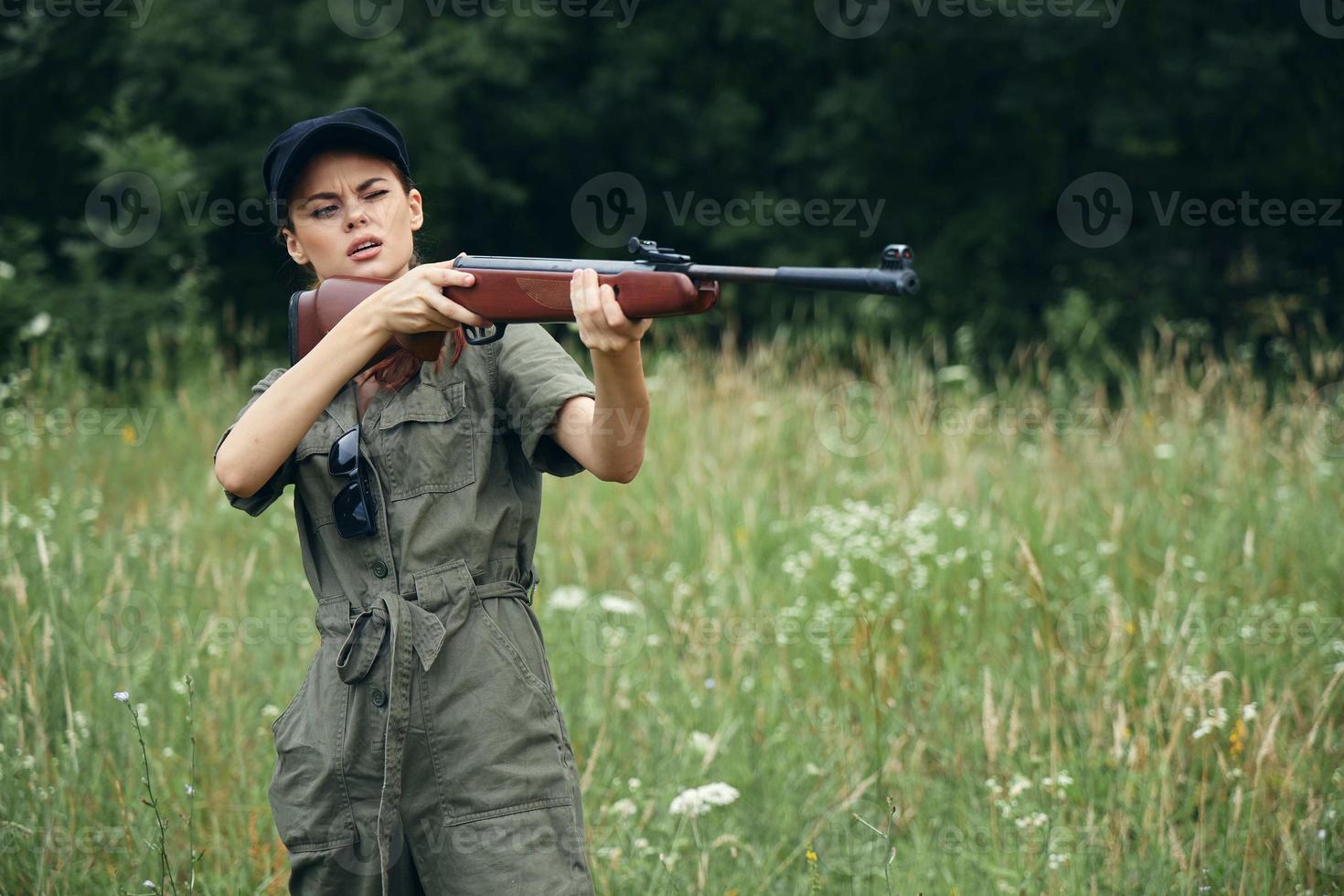 Woman soldier with a weapon in his hands, aiming, narrows his eyes black cap photo