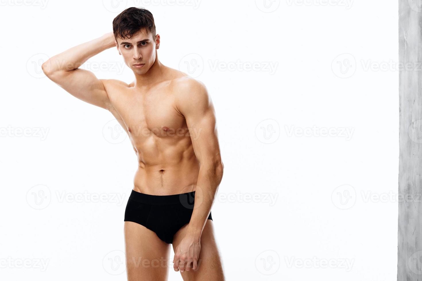 sexy athlete guy in black panties holds hand behind head and cropped view naked torso photo