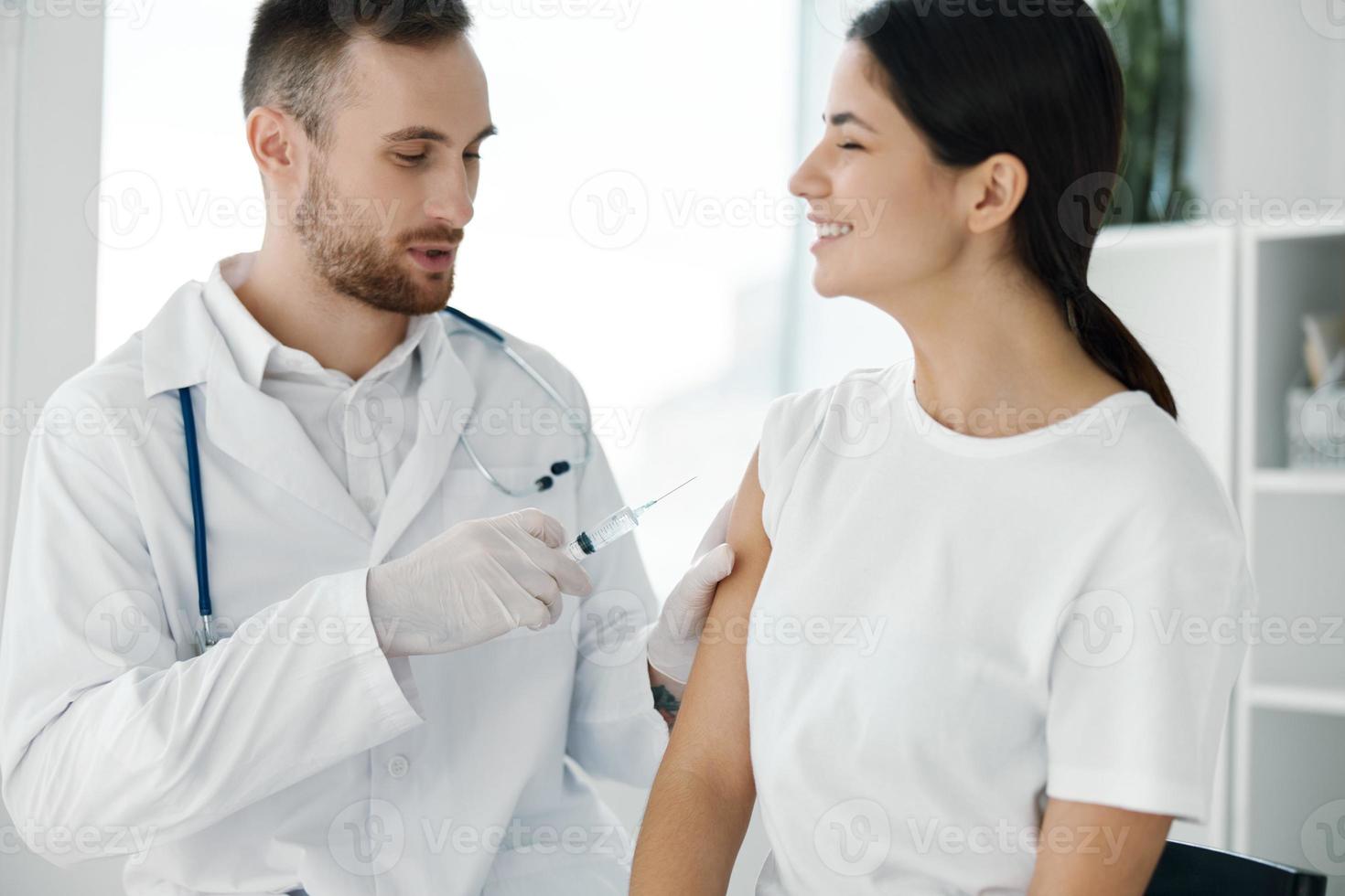 médico en protector guantes inyecta un mujer hombro desde covid-19 vacunación foto