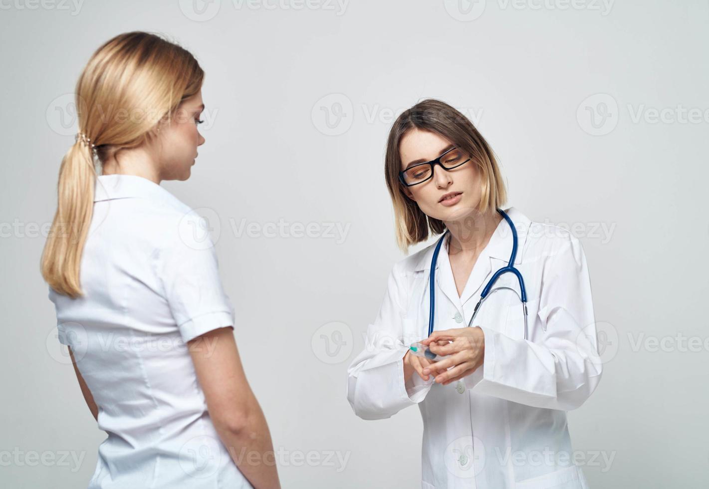 A nurse doctor in a medical gown explains something to a patient in a white T-shirt photo