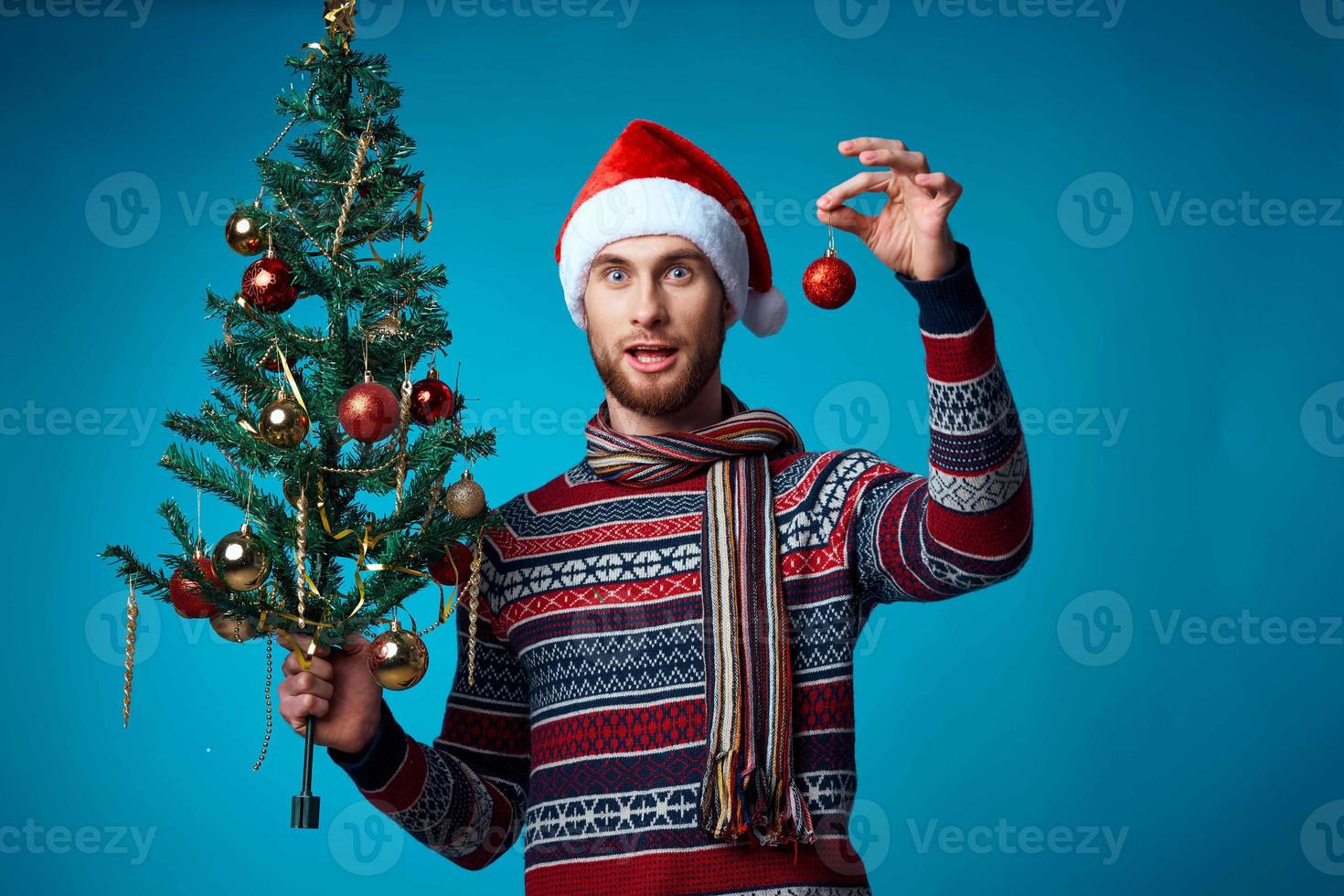 Cheerful man in a santa hat holding a banner holiday blue background photo