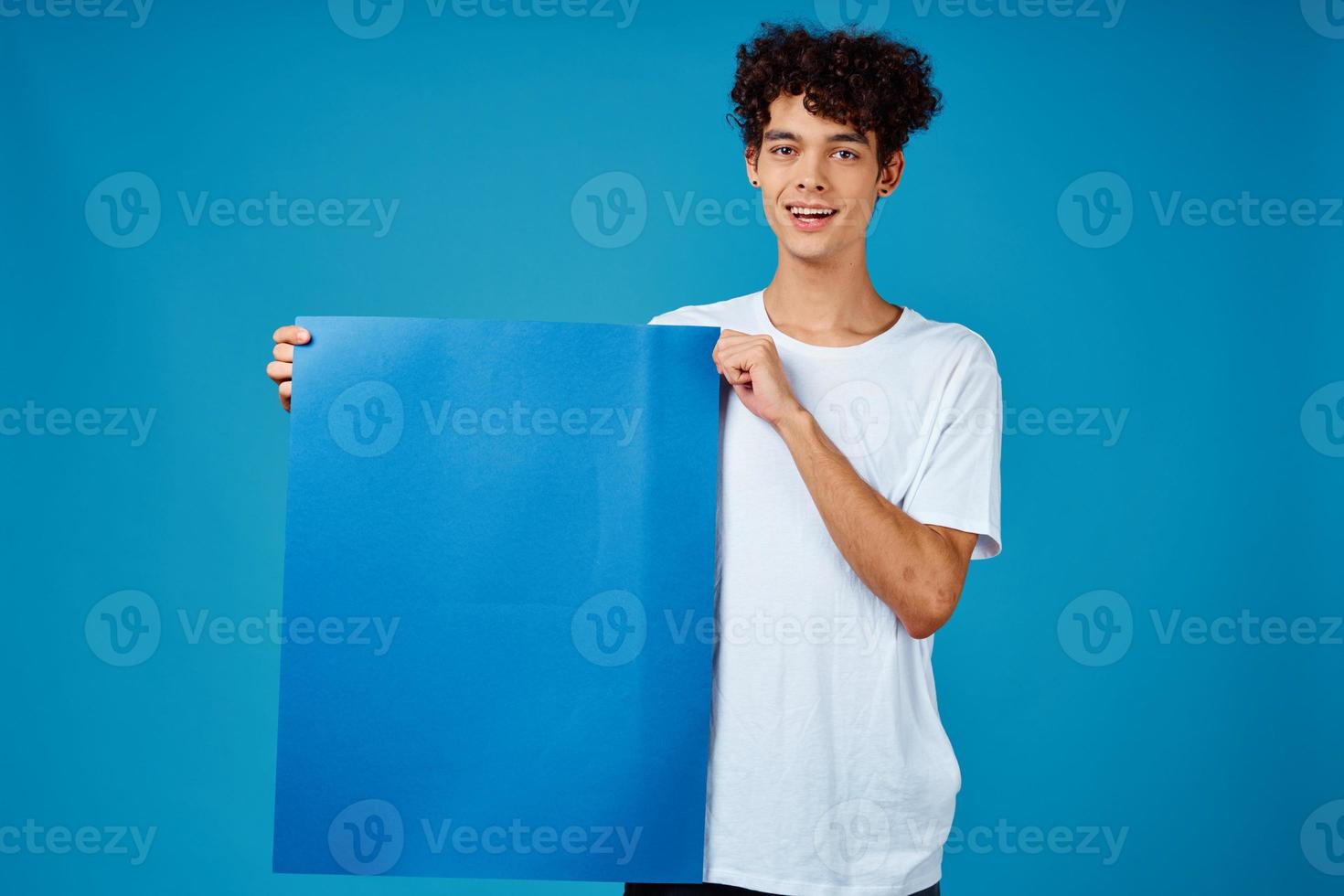 Cheerful guy with curly hair blue mockup poster advertising isolated background photo