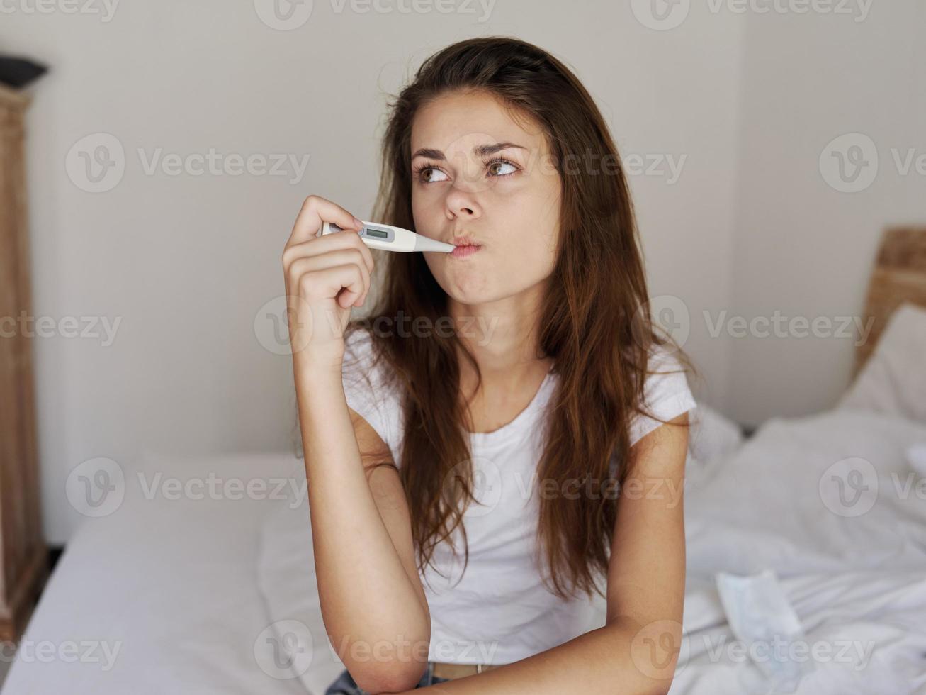 woman with a thermometer in her mouth waiting for the temperature result photo