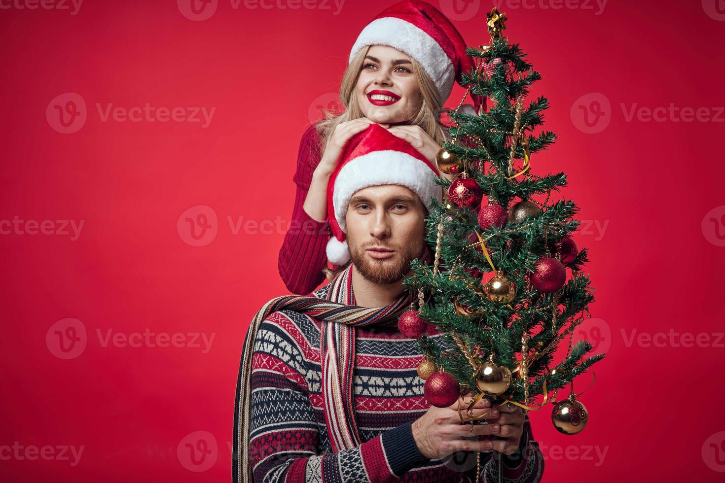 man and woman christmas tree decoration fun holiday red background photo