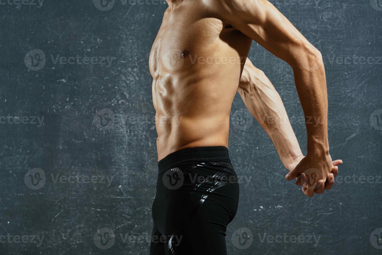 sporty man with a pumped up body workout exercises dark background photo