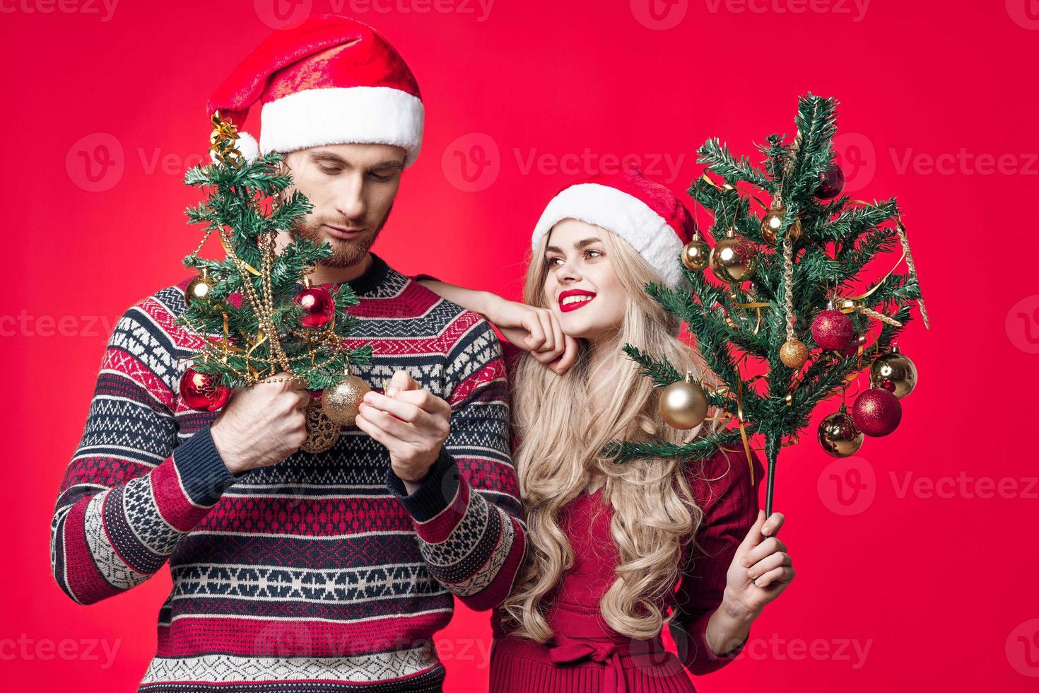 cheerful young couple in new year clothes decoration toys red background photo