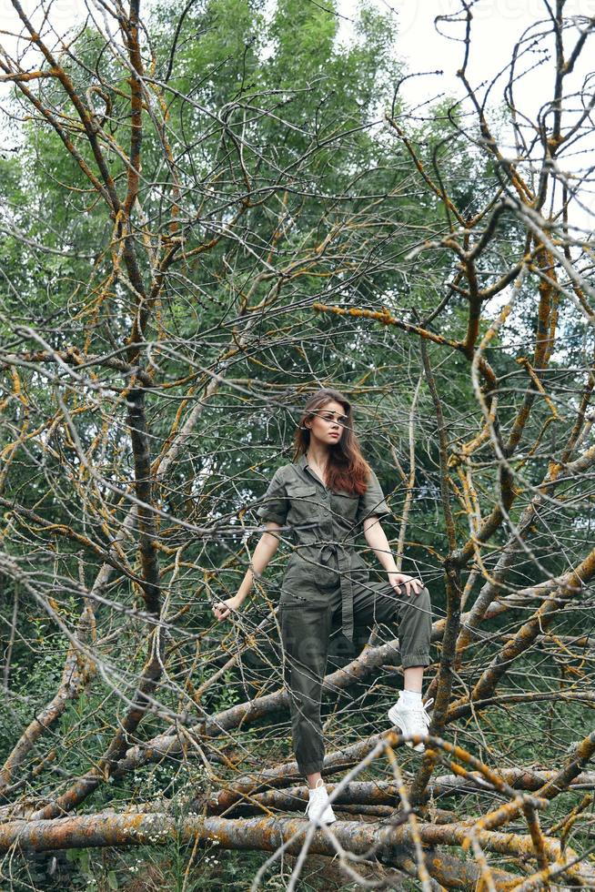 Woman on a broken tree branch in the forest and green jumpsuit sneakers photo