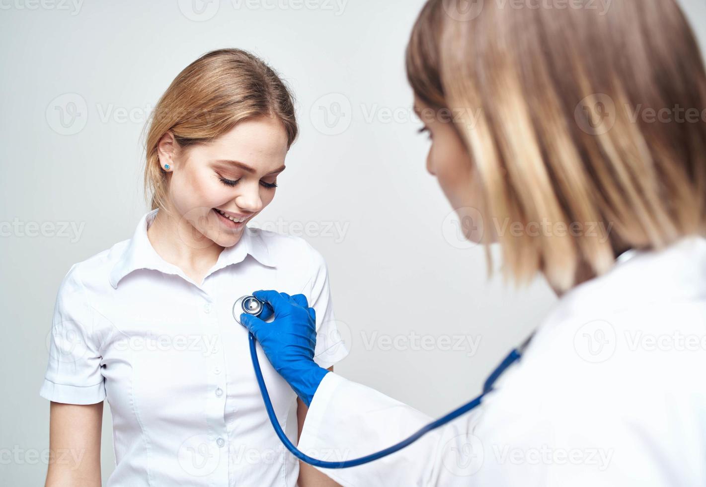 médico con un estetoscopio y un contento paciente en un ligero antecedentes foto