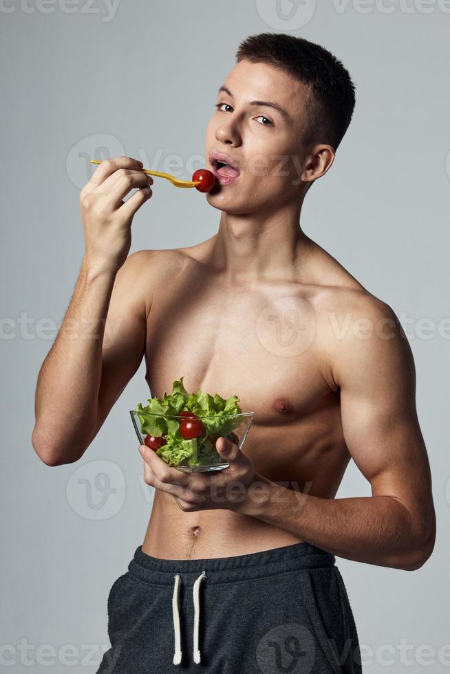 atlético chico con muscular torso comiendo ensalada salud comida dieta foto