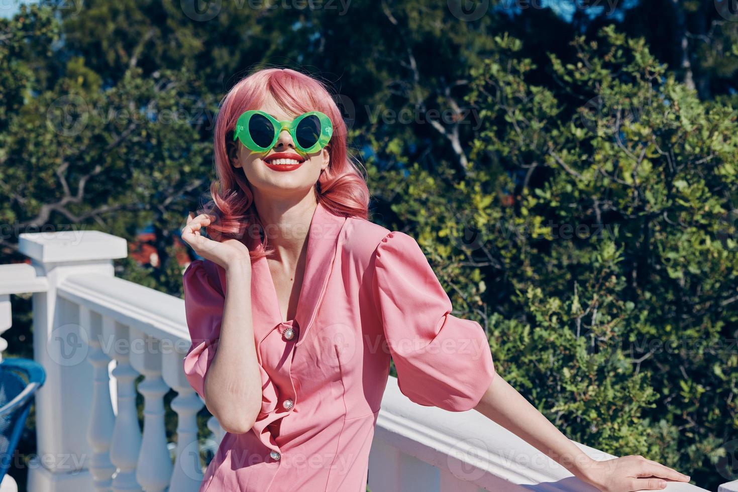 woman with pink hair in sunglasses in summer on the terrace photo