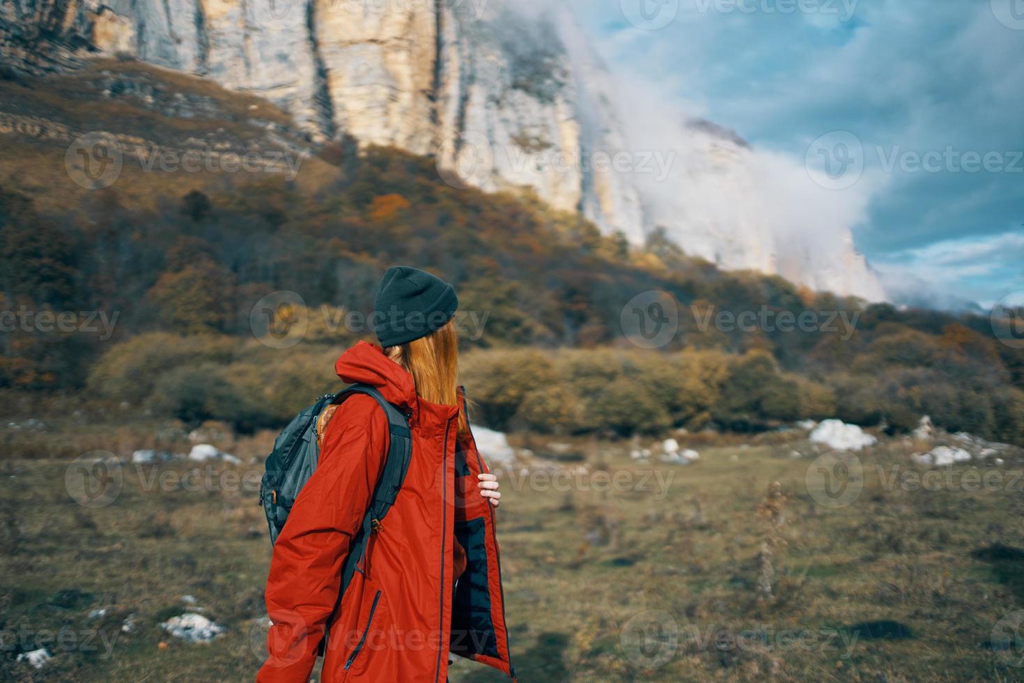 woman in jackets caps with a backpack on her back walks in the fall in the mountains and in nature photo