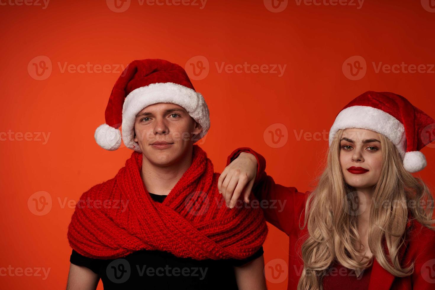 young couple in santa hats fun new year holiday red background photo