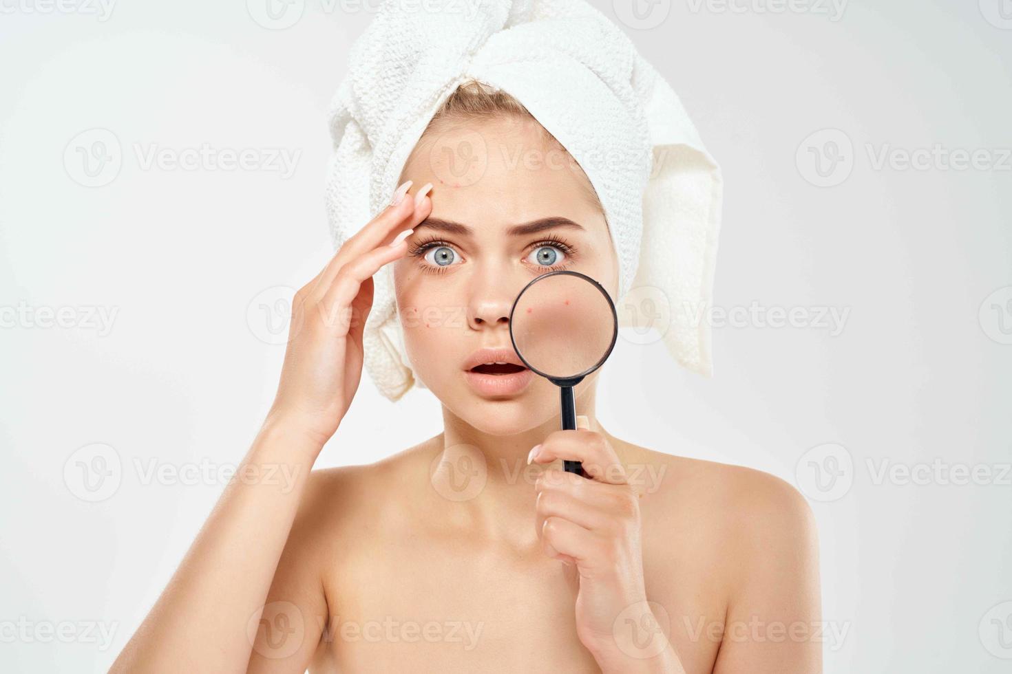 surprised woman with bare shoulders clean skin magnifying glass in hands health problems photo