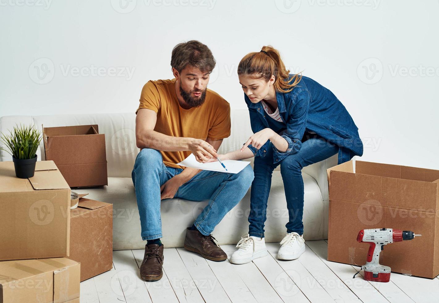 Man and woman sit on couch boxes tools rest photo