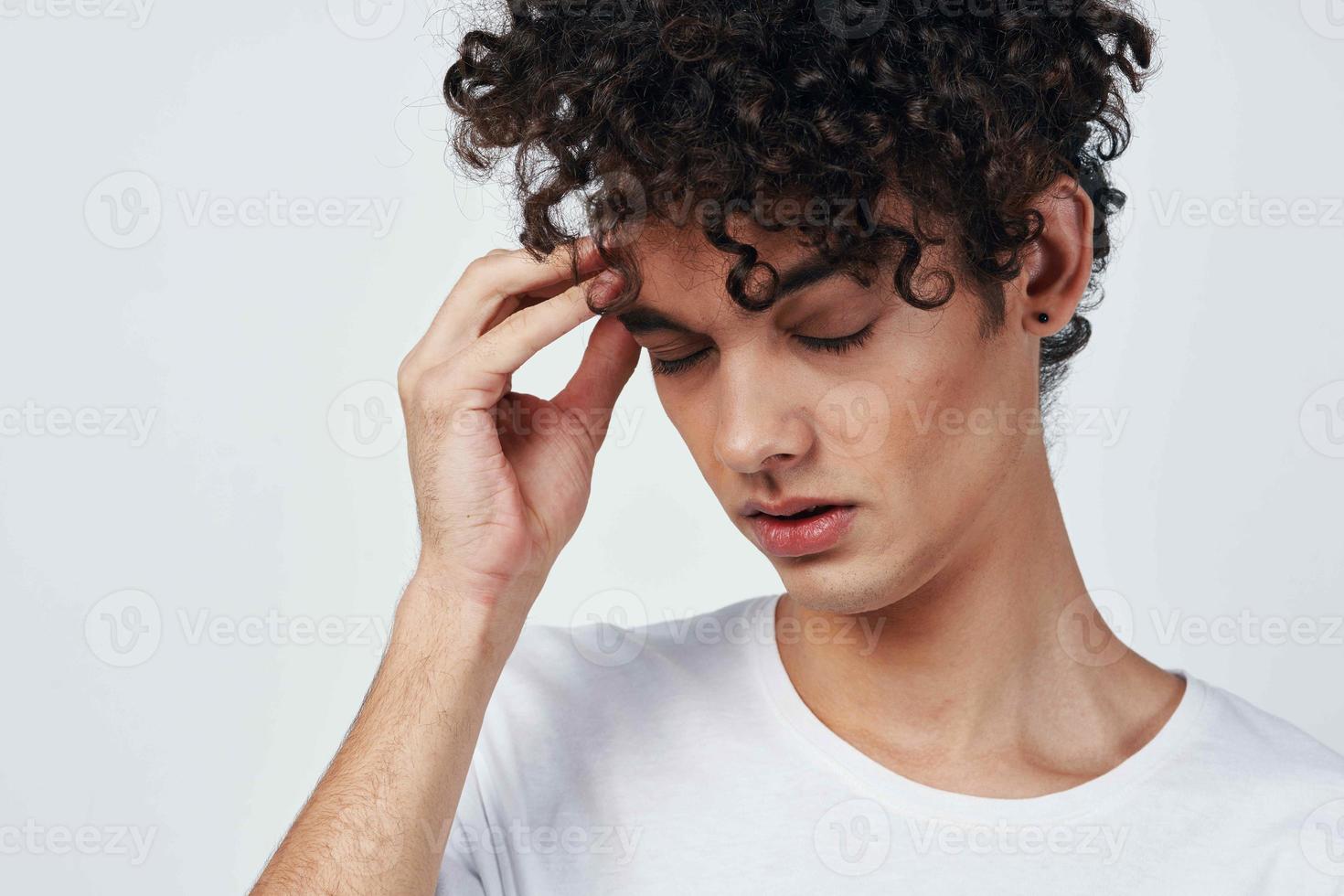 guy with curly hair in a white t-shirt headache migraine discontent photo