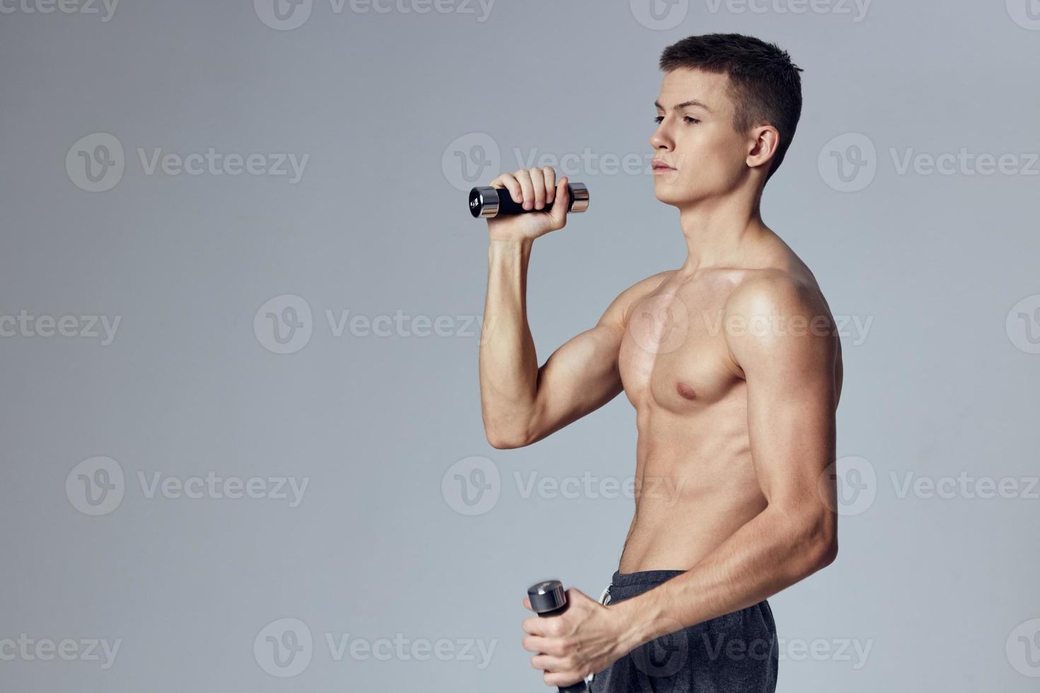 athletic man in shorts with dumbbells in his hands pumped up body fitness photo