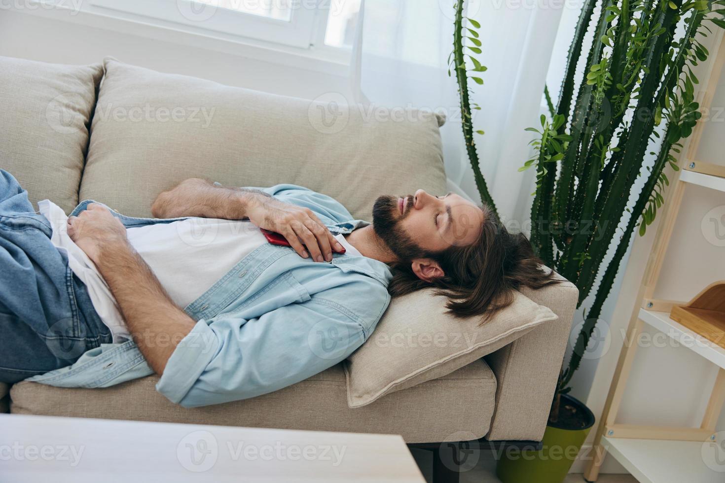 un hombre dormido en el sofá durante el día es cansado y relajado después estrés y sensación malo. estrés a trabajar, pobre dormir y salud problemas foto