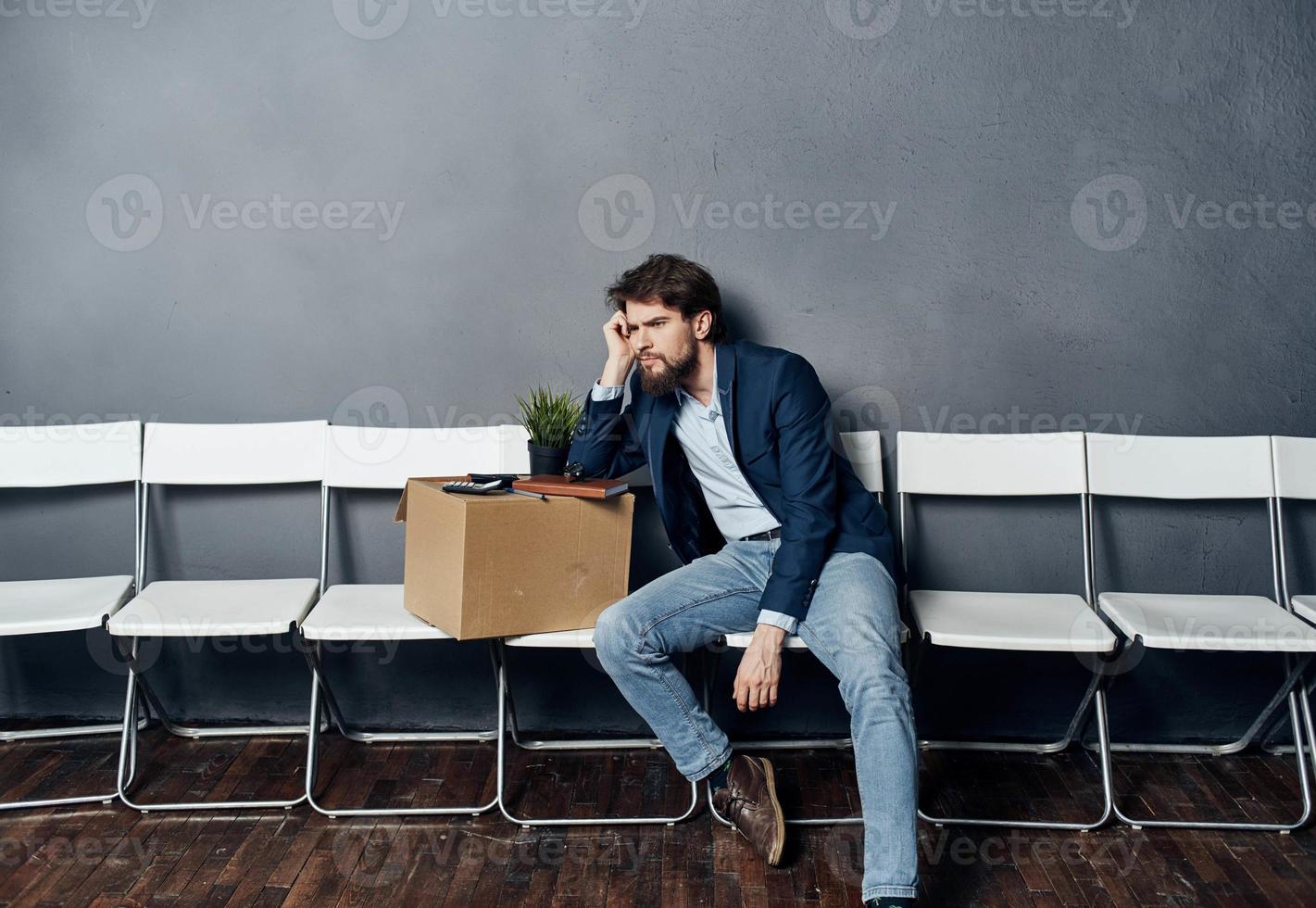 A man with things in a box sits on a chair waiting for discontent photo