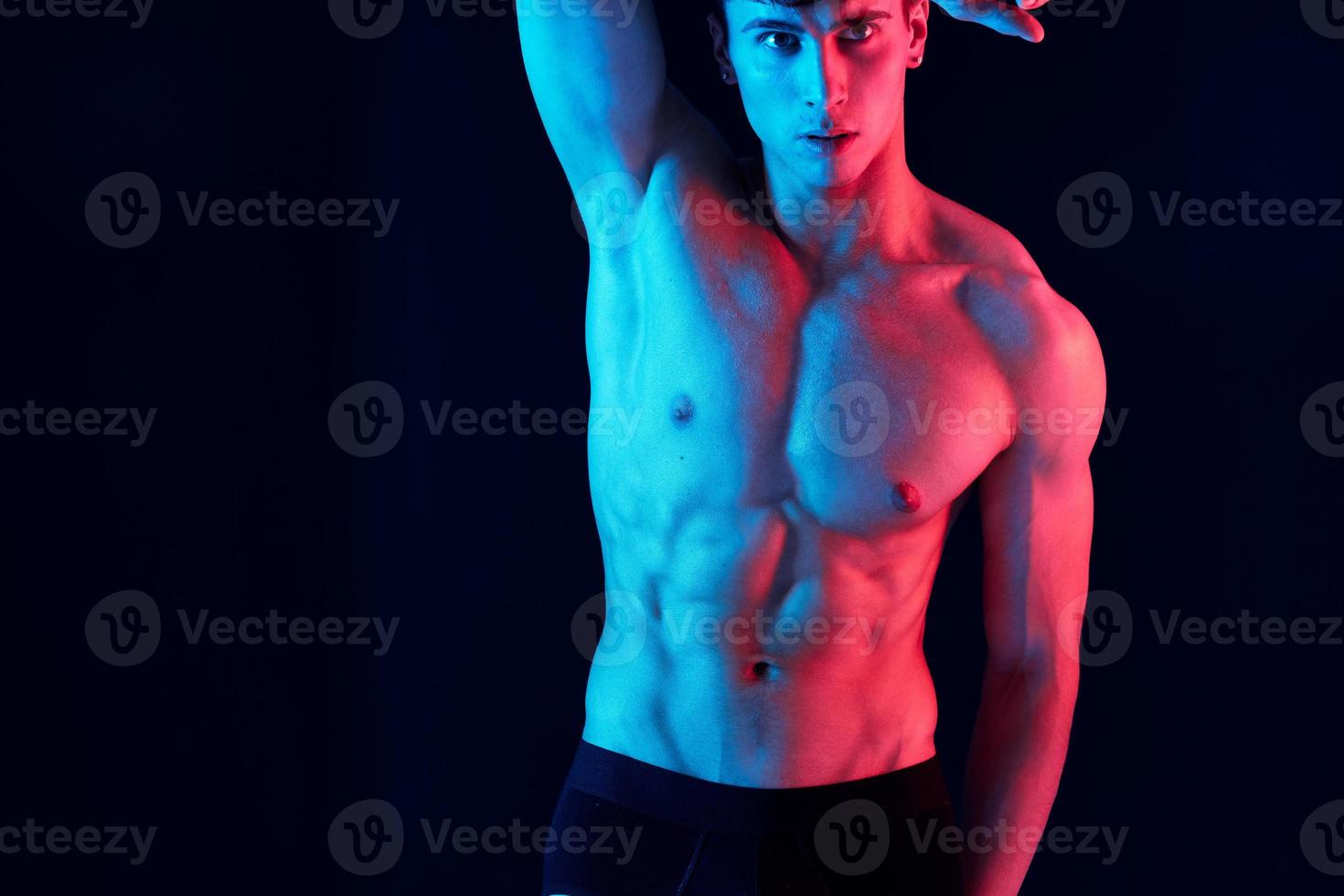 male athlete with neon skin color on isolated background holds hand behind head cropped view photo