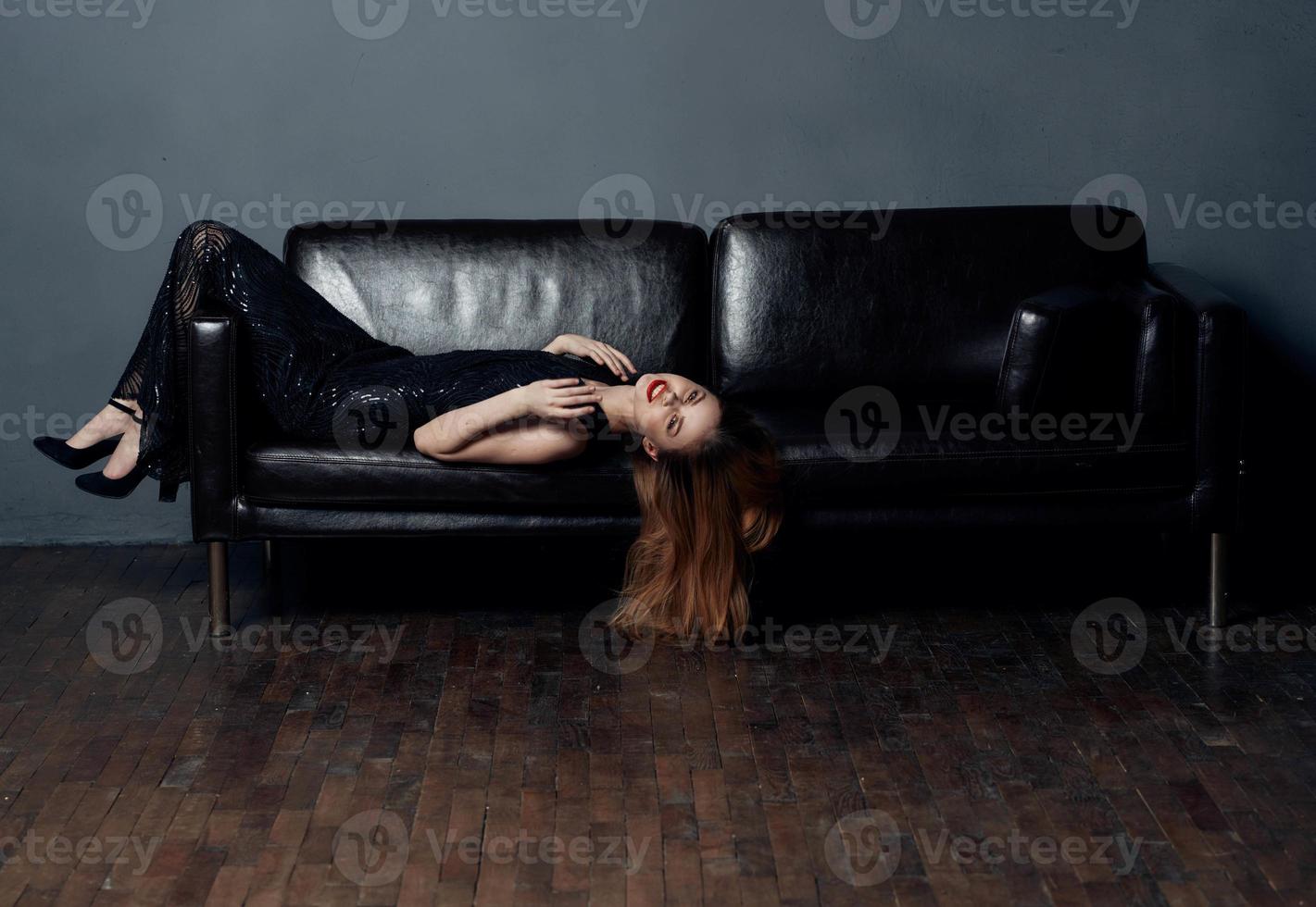 Beautiful woman with bright makeup lies on a leather sofa close-up red hair model photo