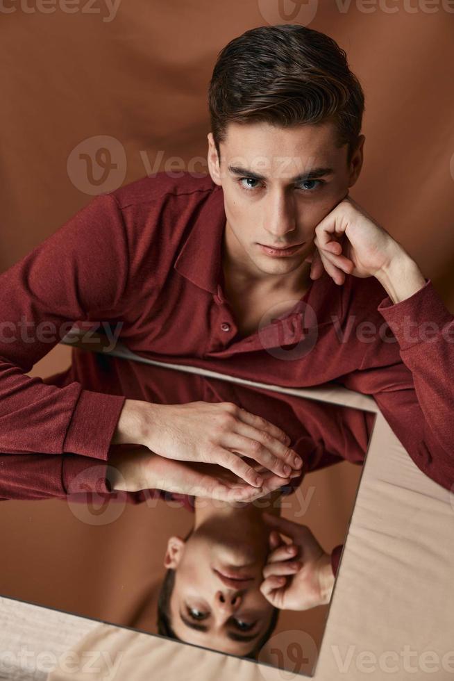 a man in a shirt sits at a table reflection in a mirror fabric background photo
