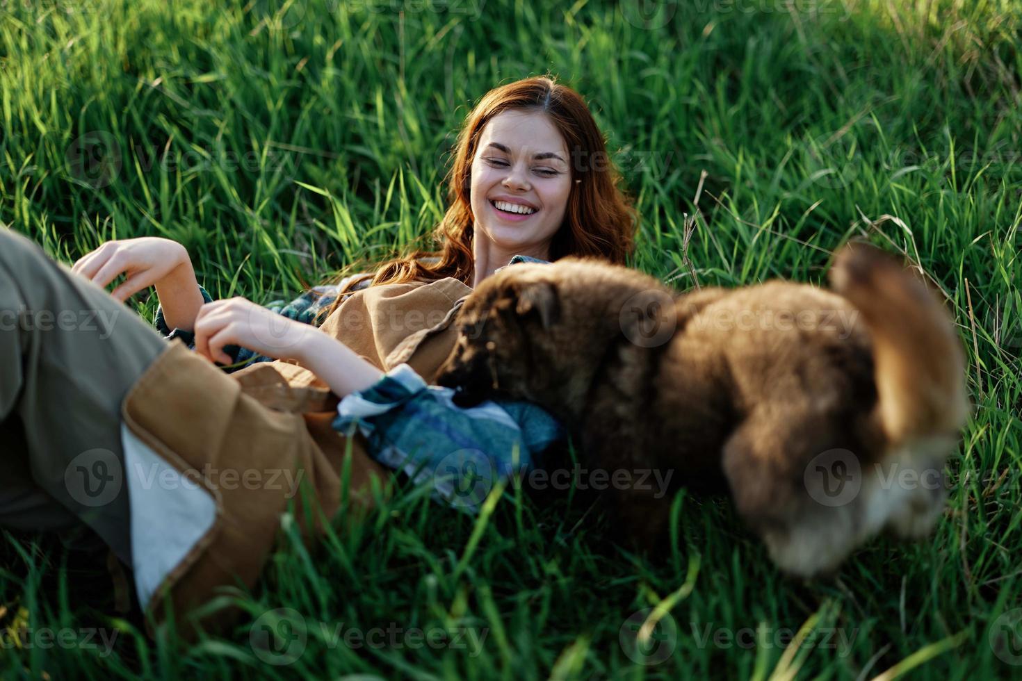 mujer juego con su perro en naturaleza sonriente y acostado en el verde césped en el parque, contento sano relación Entre amante y mascota foto