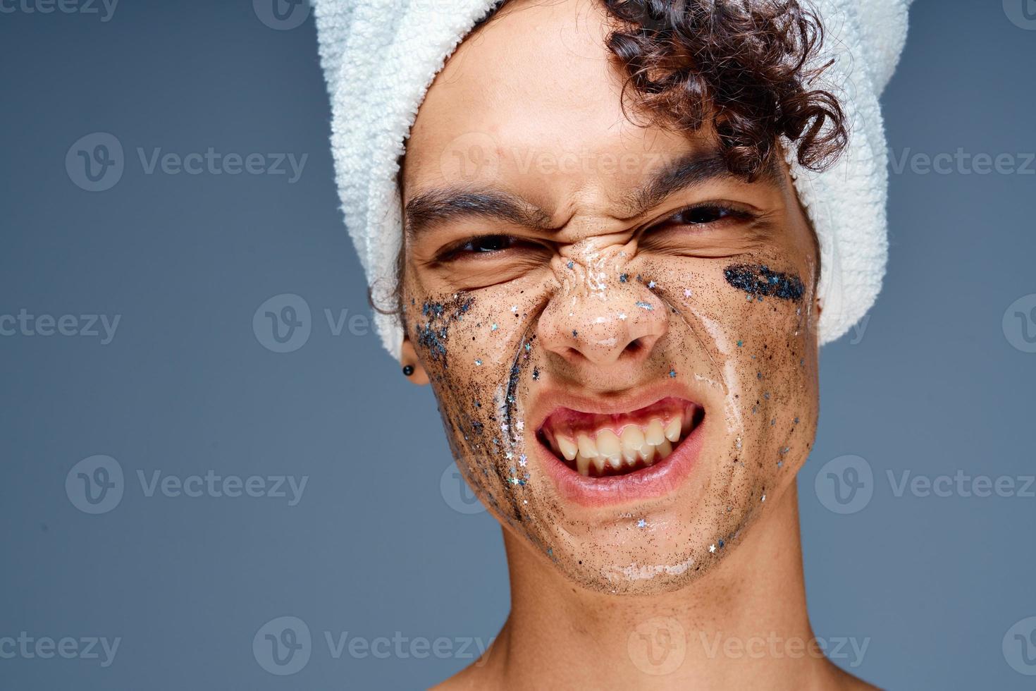 Cheerful guy with bare shoulders with a towel on his head, a black mask on his face photo