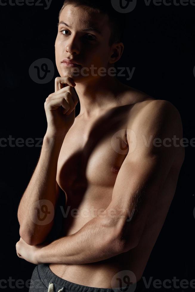 young athlete with pumped up muscles of the arms on a black background cropped view portrait photo