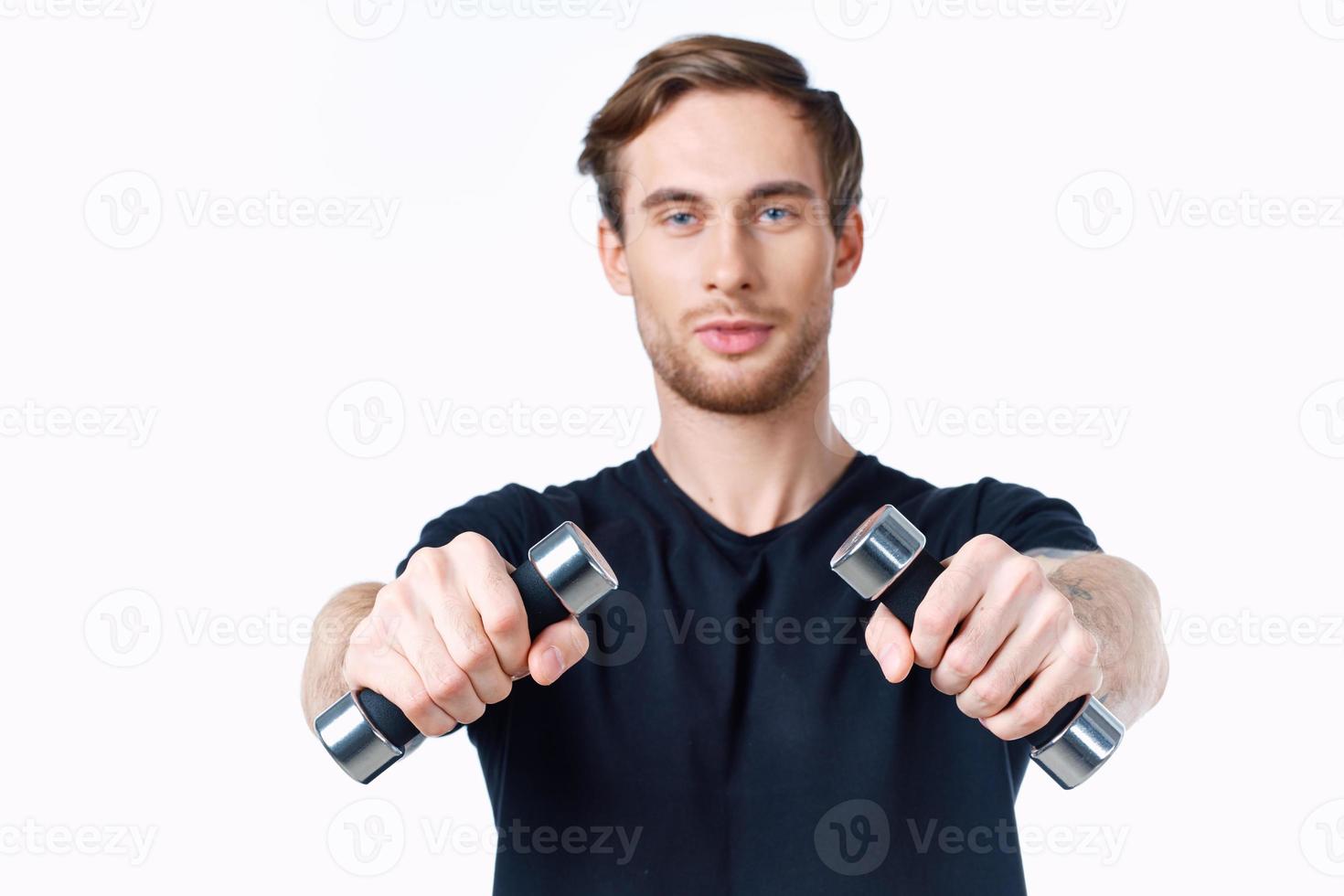 cute young man with dumbbells in hands goes in for sports on white background cropped view photo