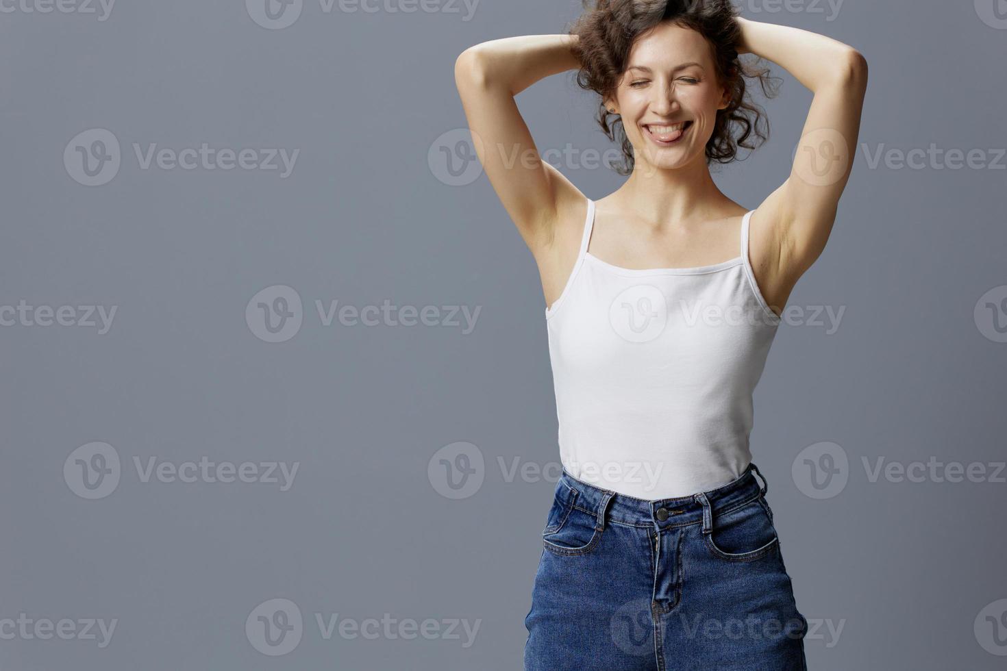 Funny curly beautiful woman in basic white t-shirt raise hair sticks tongue out posing isolated on over gray blue background. People Lifestyle Emotions concept. Copy space Free place offer photo