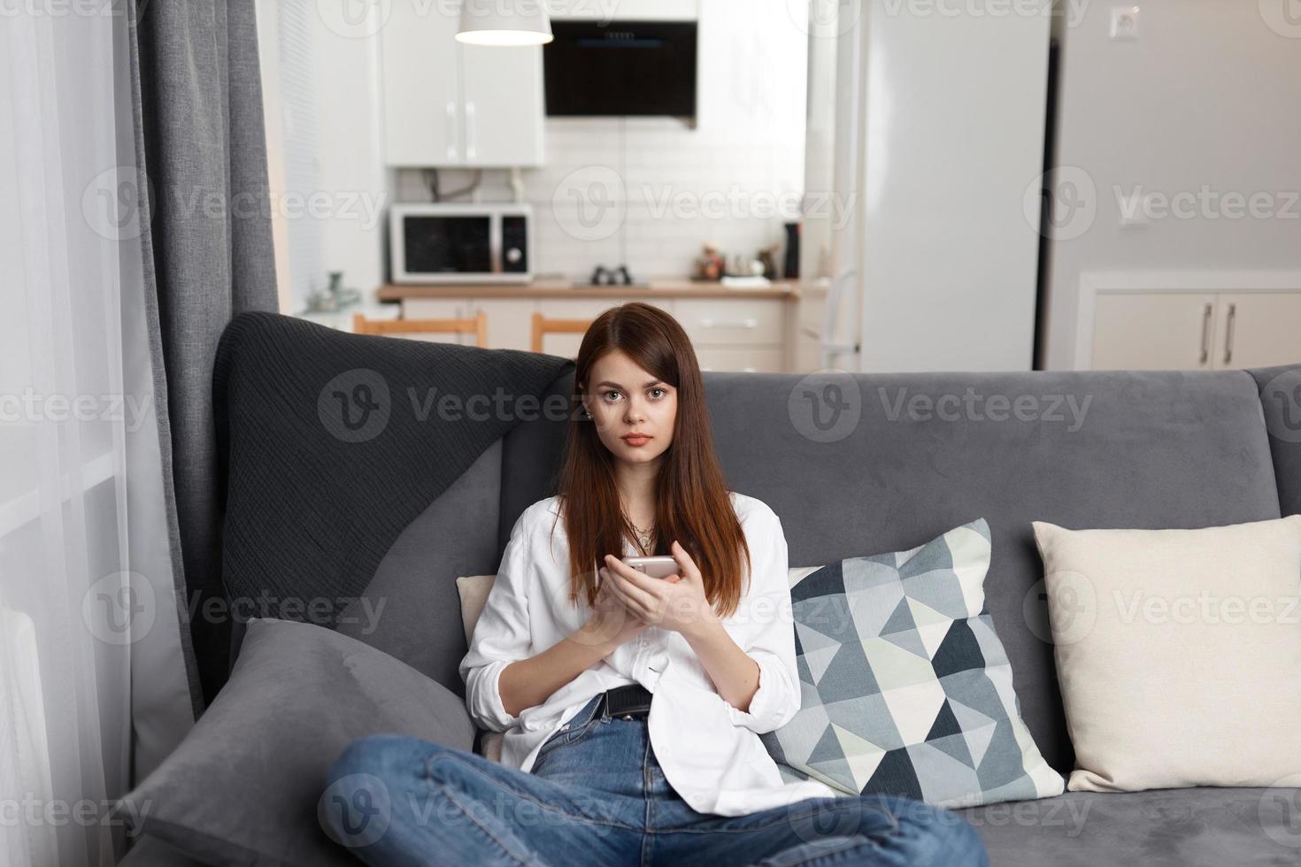 woman with a phone in her hands sitting on a comfortable sofa leisure weekend technology photo
