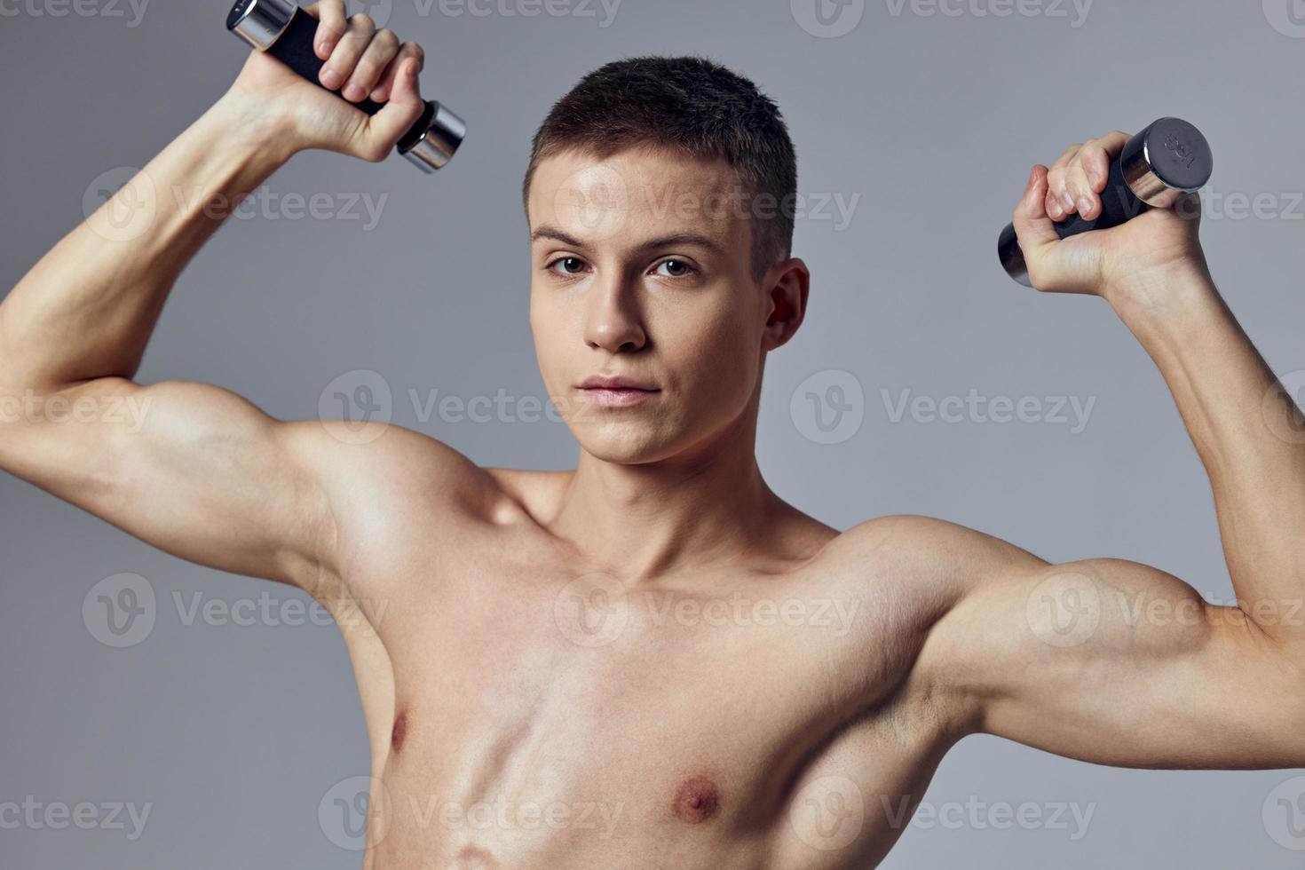 handsome man with a pumped-up body dumbbells in his hands workout muscles photo