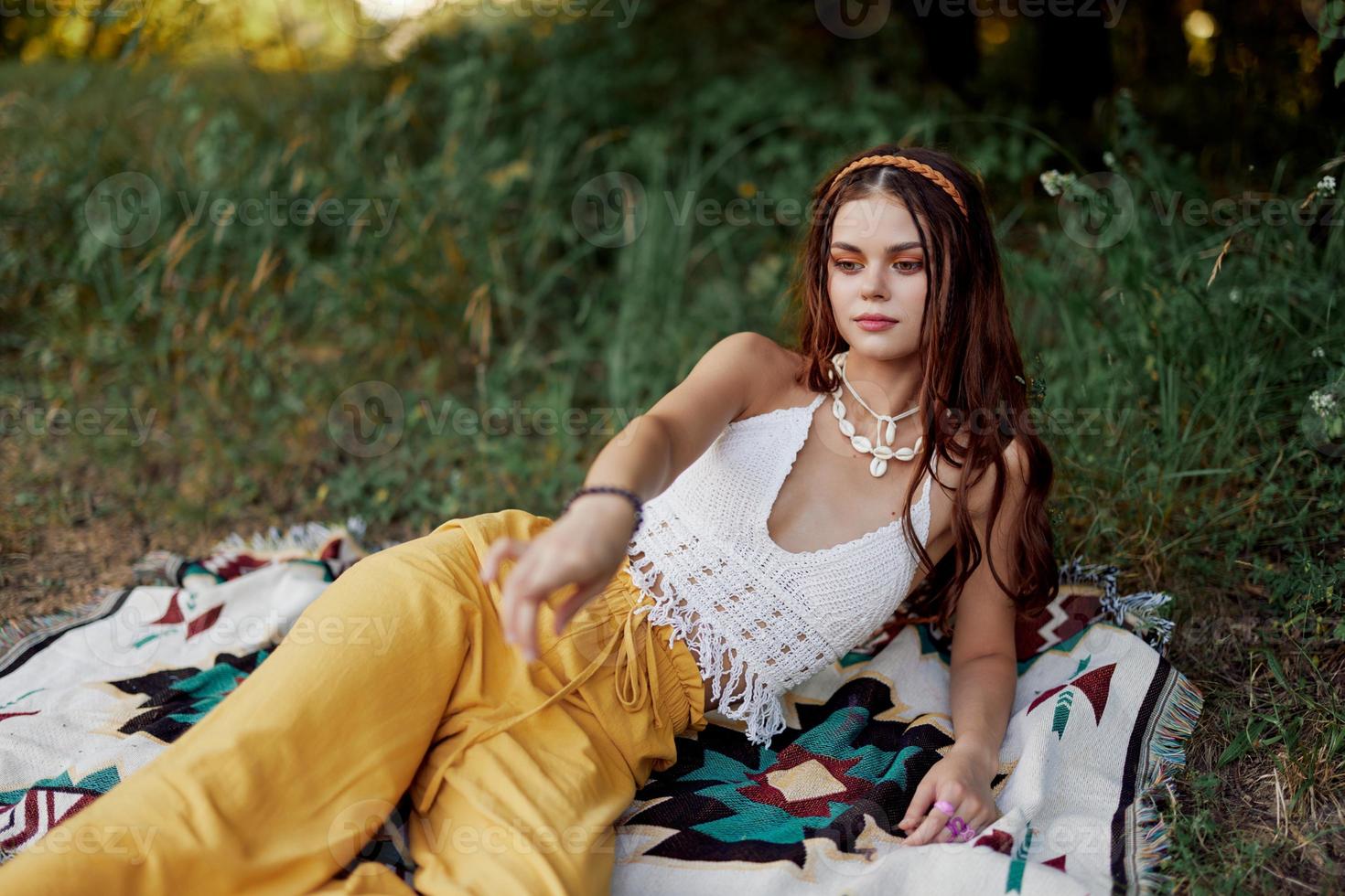 joven hermosa hippie mujer acostado en el suelo en naturaleza en el otoño en eco ropa en amarillo pantalones en el puesta de sol ligero foto