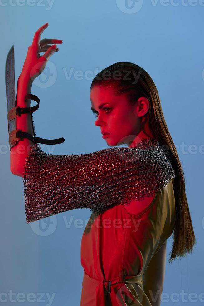 young woman Glamor posing red light metal armor on hand blue background photo