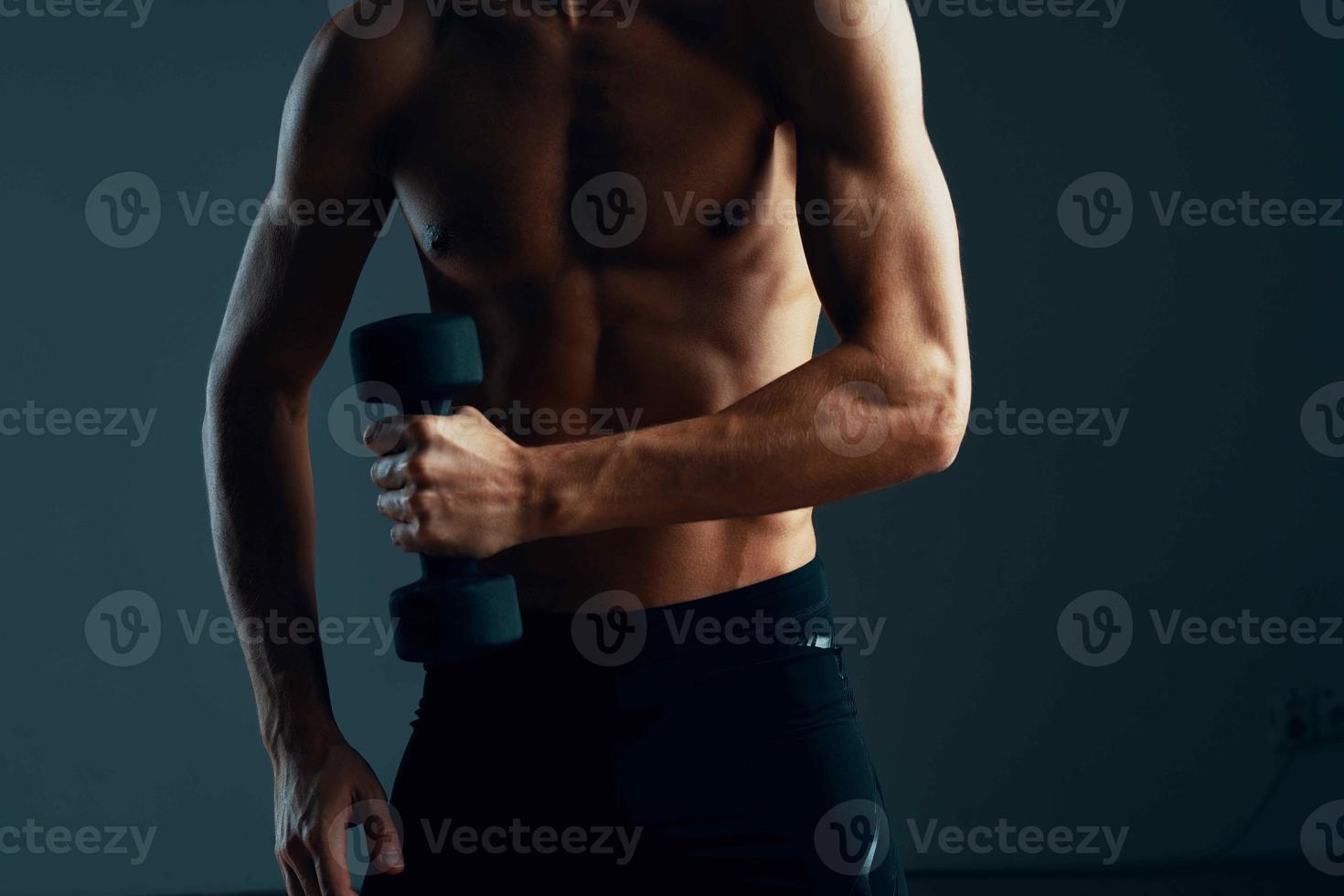 a man with a pumped up press workout with dumbbells exercises dark background photo