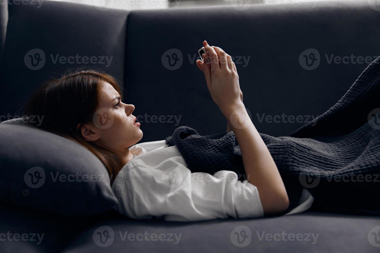 woman on sofa looking at mobile phone screen and soft pillow cropped view photo