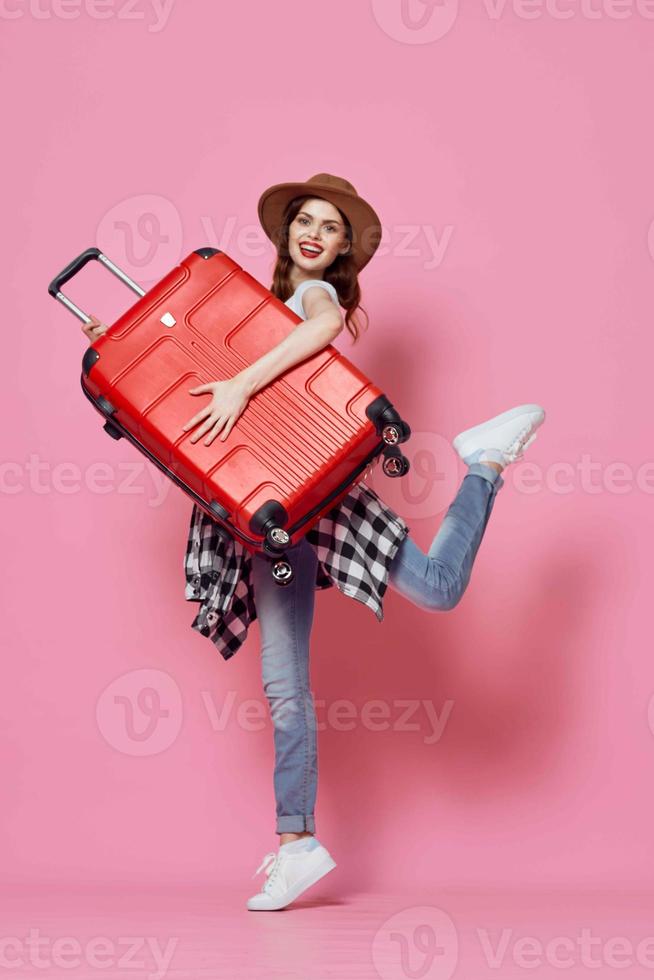 alegre mujer con rojo maleta viaje rosado antecedentes vuelo foto