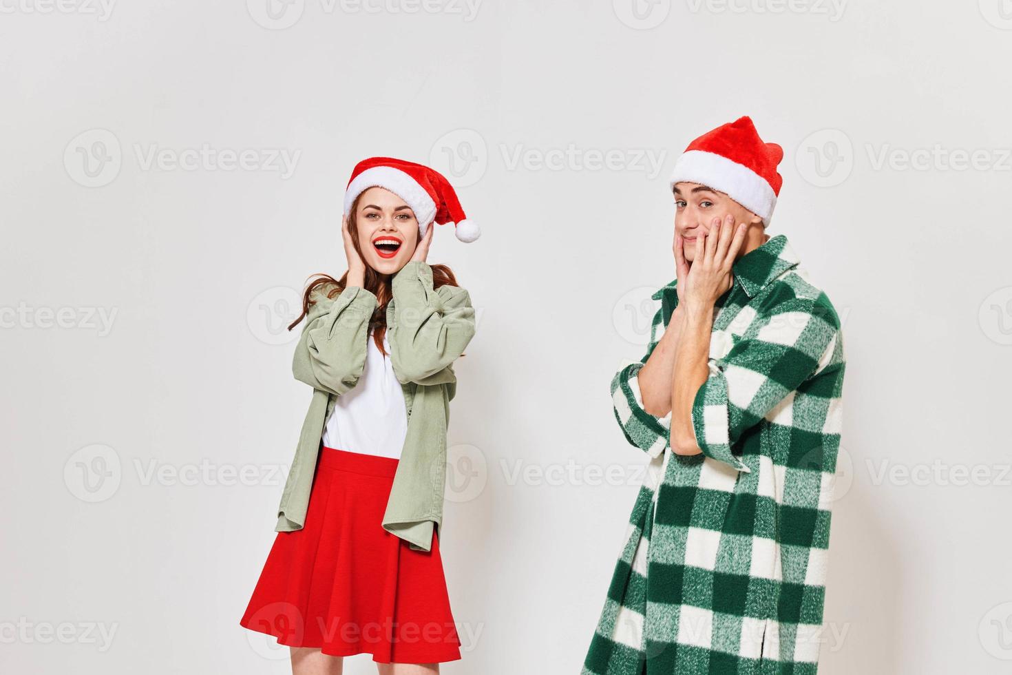 Emotional man and woman in festive hats touch their face with their hands on a light background photo