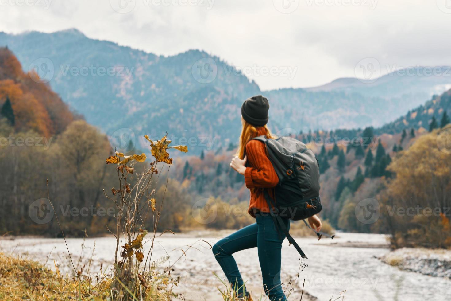 woman in a jeans sweater with a backpack rest in the mountains near the river in nature photo